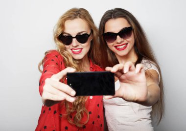 Akıllı telefonlu iki mutlu genç kadın.