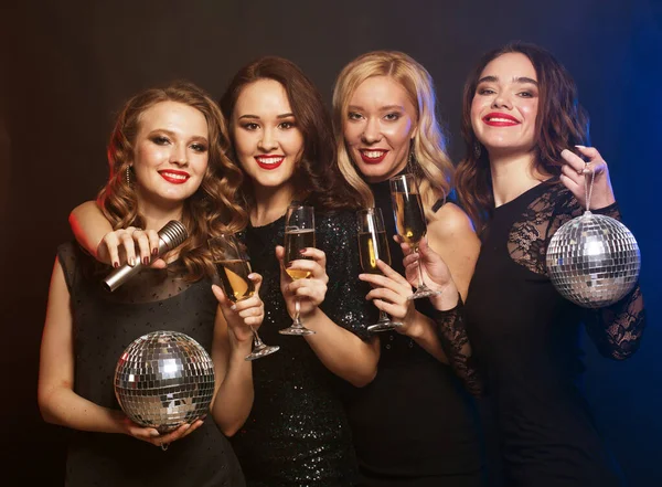 Bulizó lányok csoportja pezsgővel kattogó furulyákkal, diszkó labdákkal és mikrofonnal. — Stock Fotó
