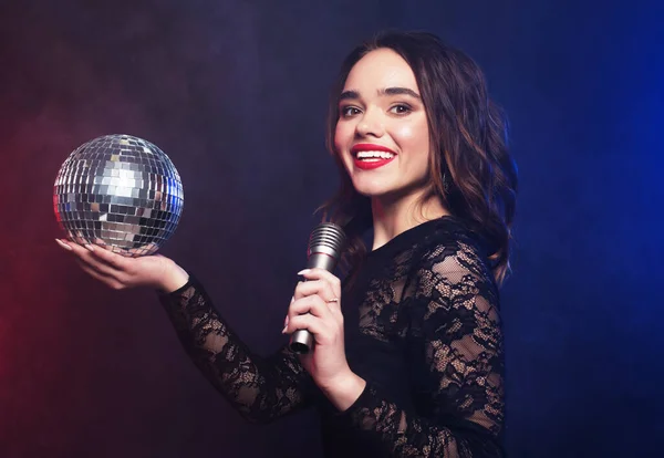 Party woman wearing black dress with disco ball and microphone — Stock Photo, Image