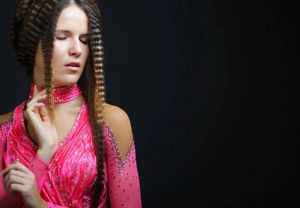 Jovem com penteado criativo vestindo vestido rosa sobre fundo preto. — Fotografia de Stock