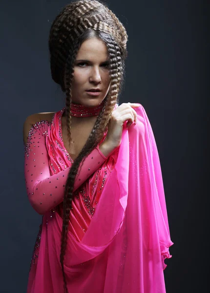 Młoda kobieta z kreatywnej fryzury noszenie różowej sukienki na czarnym tle. — Zdjęcie stockowe