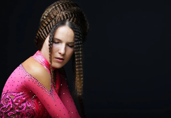 Jovem com penteado criativo vestindo vestido rosa sobre fundo preto. — Fotografia de Stock