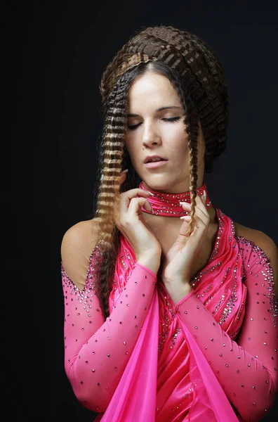 Jonge vrouw met creatieve kapsel dragen roze jurk over zwarte achtergrond. — Stockfoto