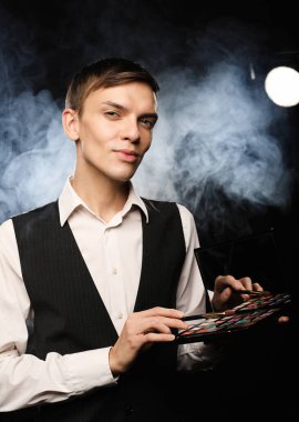 Güzellik konsepti. Stüdyoda poz veren profesyonel makyözün elinde gölgeler ve fırça paleti var..