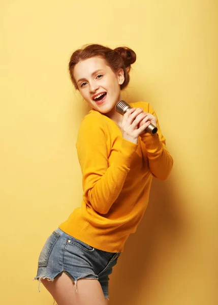 Divertente giovane rossa ragazza in giallo maglione posa isolato su sfondo giallo in studio. — Foto Stock