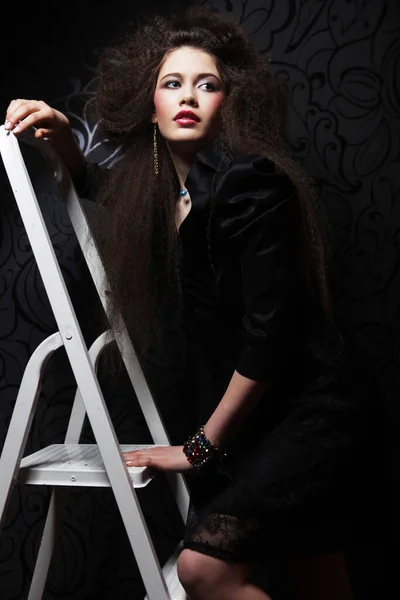 Красивая женщина с длинными кудрявыми волосами и вечерним макияжем в черном платье — стоковое фото