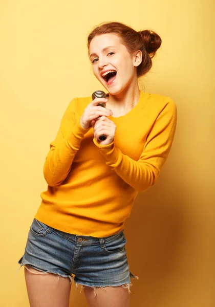 Chica pelirroja divertida joven en suéter amarillo posando aislado sobre fondo amarillo en el estudio. — Foto de Stock