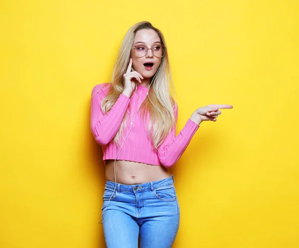 Young blond woman with hand presenting on side over yellow background — Stock Photo, Image