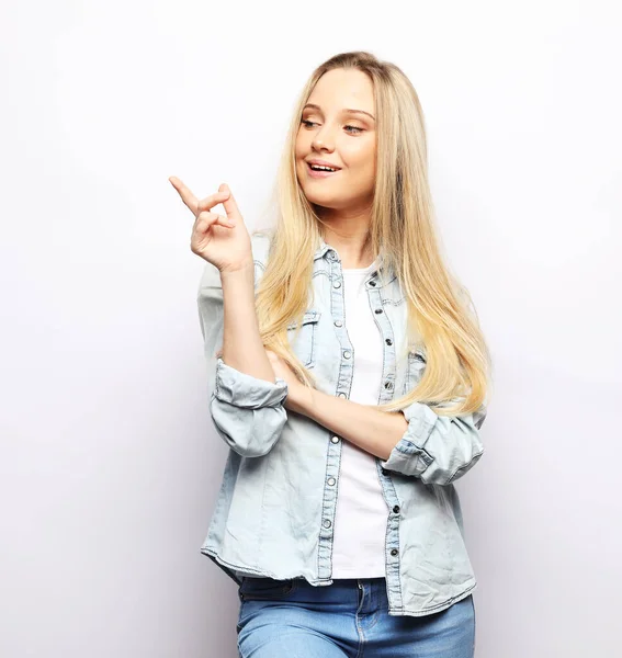 Mujer joven sonriente usando casual sobre fondo blanco señalando con el dedo —  Fotos de Stock