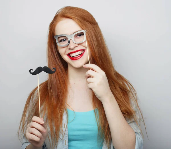 Feest, emotie en mensen concept: Aantrekkelijke jonge vrouw met snor en bril op een stokje. — Stockfoto