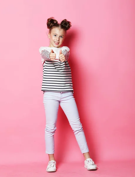 Милая маленькая девочка одета непринужденно позируя на розовом фоне — стоковое фото