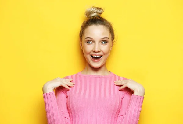 Lifestyle, emotion and people concept: Young surprised woman wearing pink shirt over yellow background — Stock Photo, Image