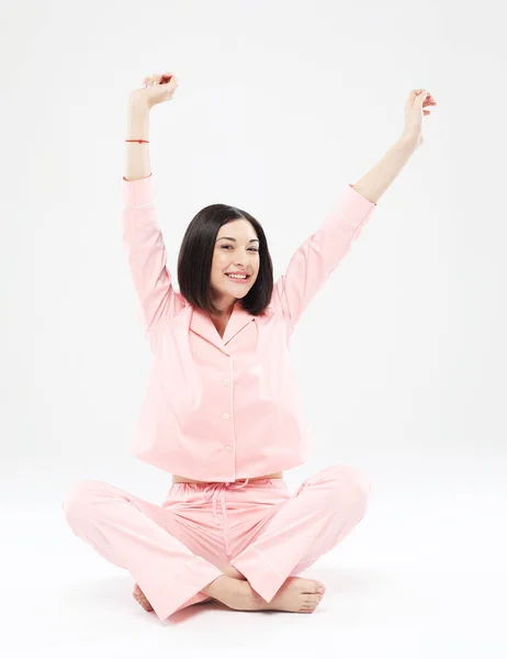 Giovane donna asiatica in pigiama rosa seduta sul pavimento e stretching, stretching, yoga, risveglio. — Foto Stock