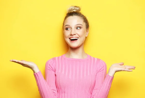 La encantadora rubia ríe y disfruta de la vida. Chica vestida con un jersey rosa posando sobre un fondo amarillo. — Foto de Stock