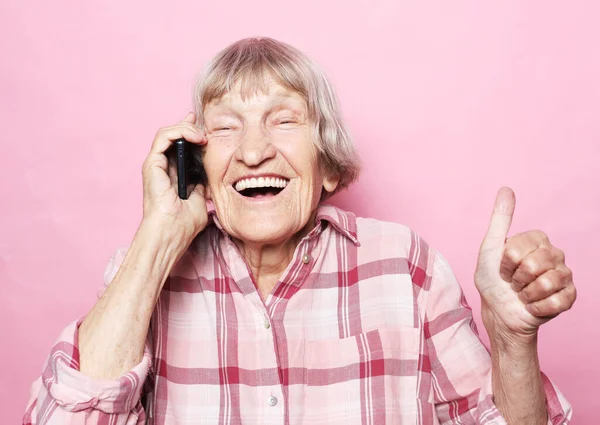 Mulher velha usar smartphone impressionado mídias sociais como feedback ganhar levantar punhos gritar sim isolado sobre fundo rosa — Fotografia de Stock