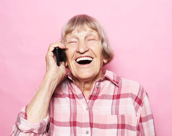 Mulher idosa alegre falando ao telefone sobre fundo rosa — Fotografia de Stock