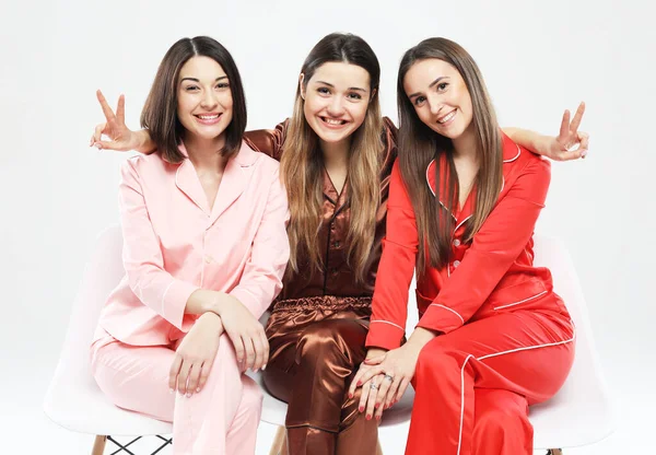 Pijama giymiş üç güzel kız arkadaş sandalyeye oturup kameraya poz veriyor.. — Stok fotoğraf