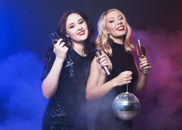 Due giovani donne in possesso di un bicchiere di vino e discoteca palla al night club — Foto Stock
