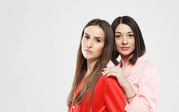 Estilo de vida, la amistad y el concepto de la gente - dos hermosas chicas vestidas en pijama abrazando y sonriendo —  Fotos de Stock