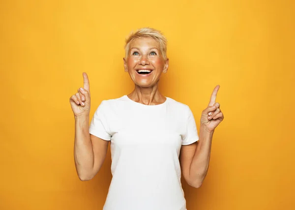 Senior woman with short hair pointing with fingers and raised arms. — Stock Photo, Image