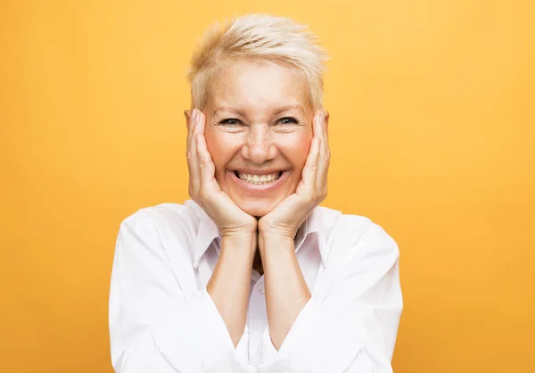 Portrait of senior woman with cute smile over yellow background — Stock Photo, Image