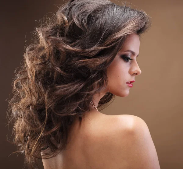 Brunette fille aux cheveux bouclés longs, sains et brillants. Belle femme modèle avec coiffure ondulée. Soins et beauté. — Photo