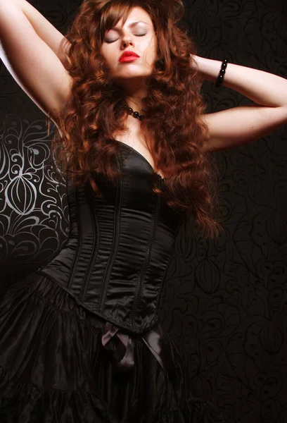 Urocza Femme Fatale Brunetka Czarnej Sukience Długimi Kręconymi Włosami Studio — Zdjęcie stockowe