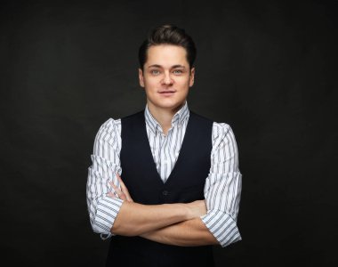 Elegante yakışıklı adam el ele tutuşuyor ve siyah arka planda kameraya bakıyor.