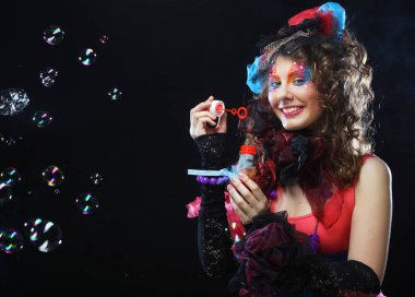 Yaratıcı makyajlı bir model sabun köpüğü üflüyor. Bebek stili.