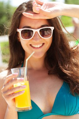 Bir bardak portakal suyuyla rahatlatıcı esmer kadının yaz portresi.