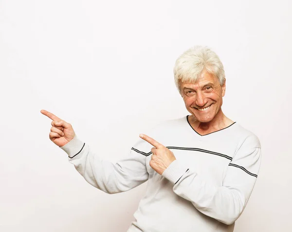 Lifestyle, emotie en bejaardenconcept - Happy senior man show something over white background — Stockfoto