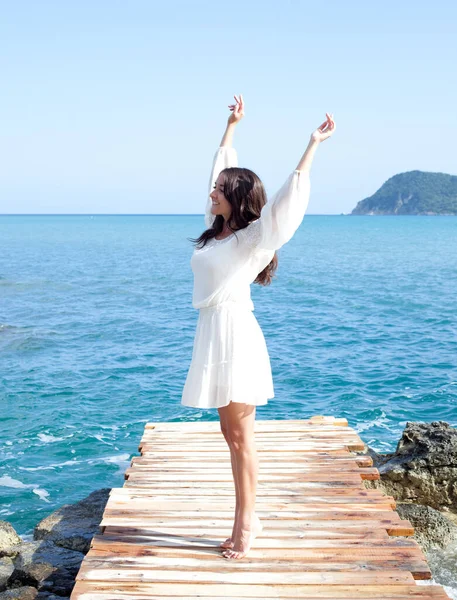 Joven morena feliz en el puente cerca del mar, hora de verano. — Foto de Stock