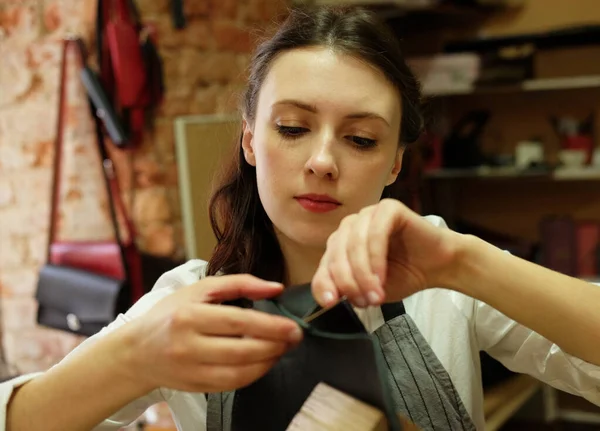 Fiatal nő dolgozik egy táska készítő stúdióban, kivágja a részleteket — Stock Fotó
