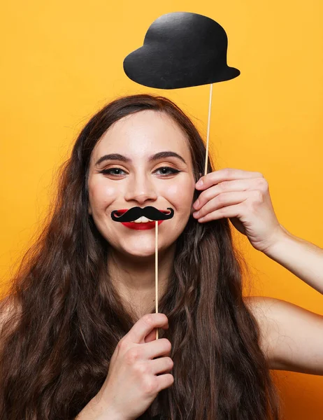 Junge brünette Frau mit Schnurrbart und Hut auf einem Stock über gelbem Hintergrund. — Stockfoto