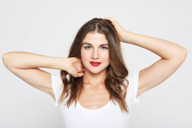 Yaşam tarzı, duygu ve insan konsepti: Genç, şaşırmış kadın gülümseyip saçlarına dokunuyor