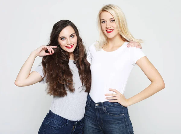 Estilo de vida y el concepto de la gente: Dos amigas jóvenes de pie juntos y divirtiéndose. Mirando la cámara. — Foto de Stock