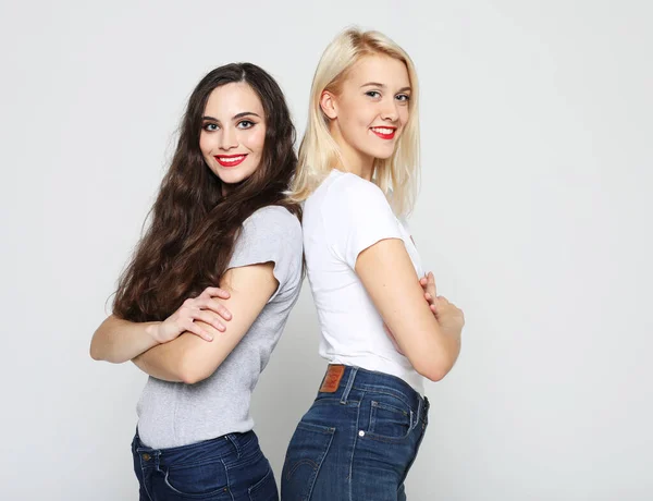 Estilo de vida y el concepto de la gente: Dos amigas jóvenes de pie juntos y divirtiéndose. Mirando la cámara. —  Fotos de Stock