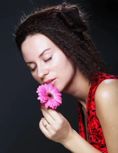 Ung vacker kvinna bär röd klänning håller rosa gerber blomma — Stockfoto