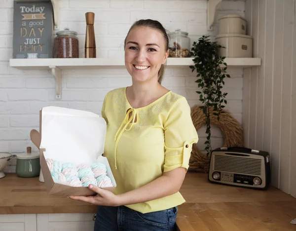 Egy fiatal pék nő pillecukrot tart a kezében. Boldog, mosolygós és vidám.. — Stock Fotó