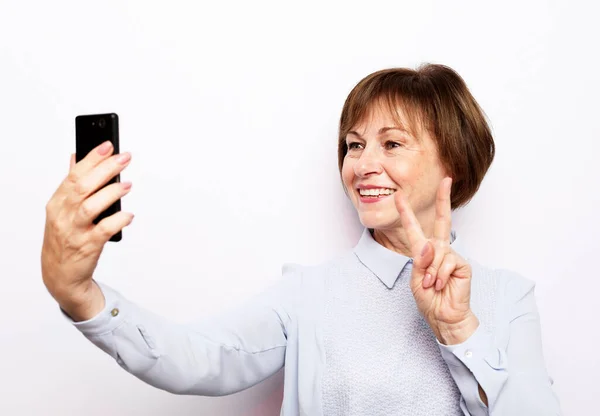 Fotografie bláznivé extatické staré ženy použít smartphone dojem sociálních médií, jako je zpětná vazba win raise pěsti křik ano izolované přes bílé pozadí — Stock fotografie