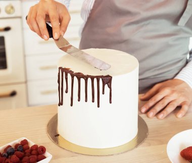 Kadın pasta dekorasyonuyla meşgul, küçük bir ev işi.