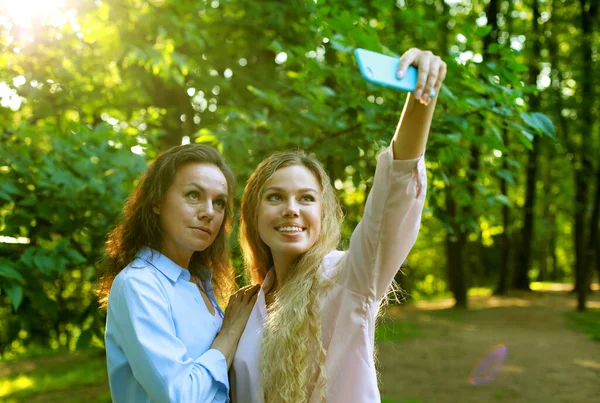Estilo de vida, família e conceito de pessoas: mãe madura e filha adulta estão fazendo selfie por telefone celular no parque de verão — Fotografia de Stock