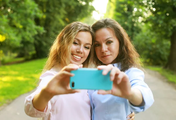Стиль життя, сім'я і люди концепція: зріла мати і доросла дочка роблять селфі на мобільному телефоні в літньому парку — стокове фото