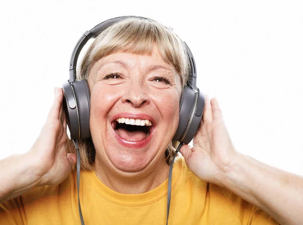 Wesoła starsza kobieta słuchająca muzyki ze słuchawkami na białym tle — Zdjęcie stockowe