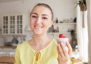 Genç fırıncı kadın elinde böğürtlenli kek tutuyor. Mutlu, gülümseyen ve neşeli.