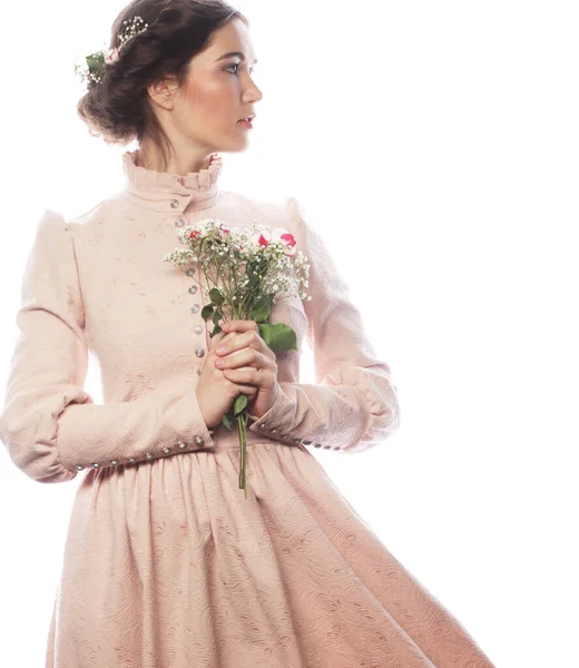 Young brunette woman in pink dress holding a bouquet of roses and dreaming of love — Stock Photo, Image