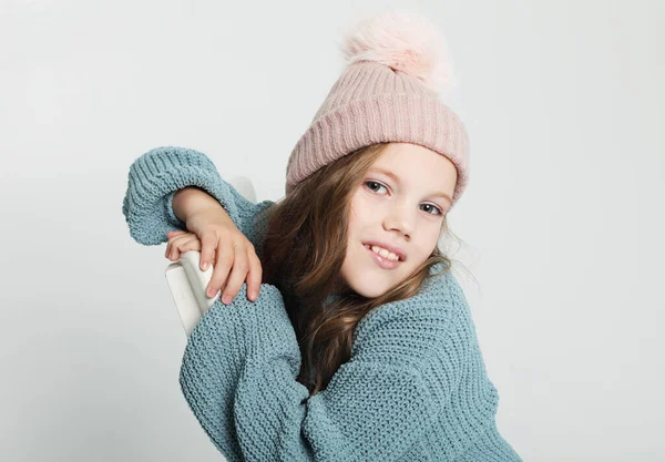 Маленький ребенок в синем свитере и зимней шляпе улыбается и смотрит в камеру. — стоковое фото