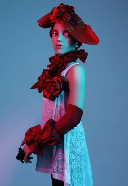 Şık giyinmiş güzel bir kız çocuğu. Kırmızı şapka, atkı, bilezik, neon ışığı, moda konsepti.