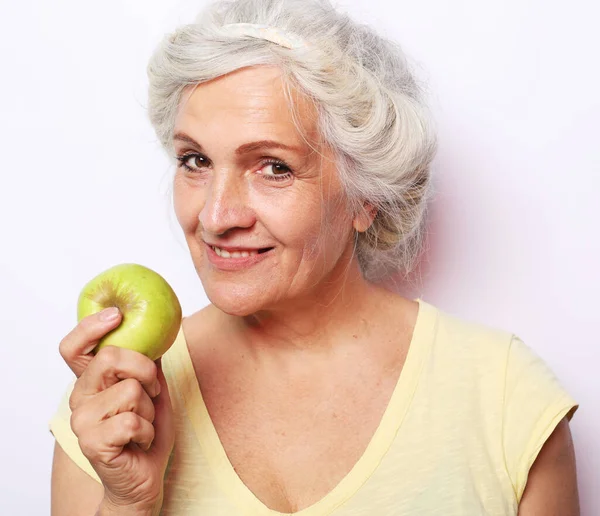 Portrét krásné starší ženy držící jablko, usmívající se, izolované na bílém pozadí. — Stock fotografie