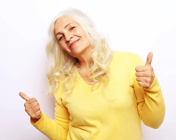 Dobrá nálada šťastný úsměv pozitivní starší žena s bílými vlasy, na sobě žlutý svetr show palce nahoru — Stock fotografie